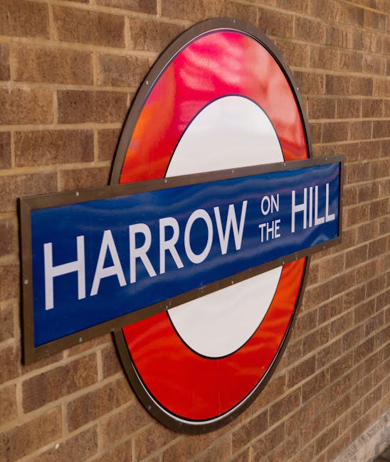 A photograph of the London Underground sign mounted on a brick wall, featuring a red circular border with a white center and a blue rectangular sign overlay that displays the text 'HARROW ON THE HILL'