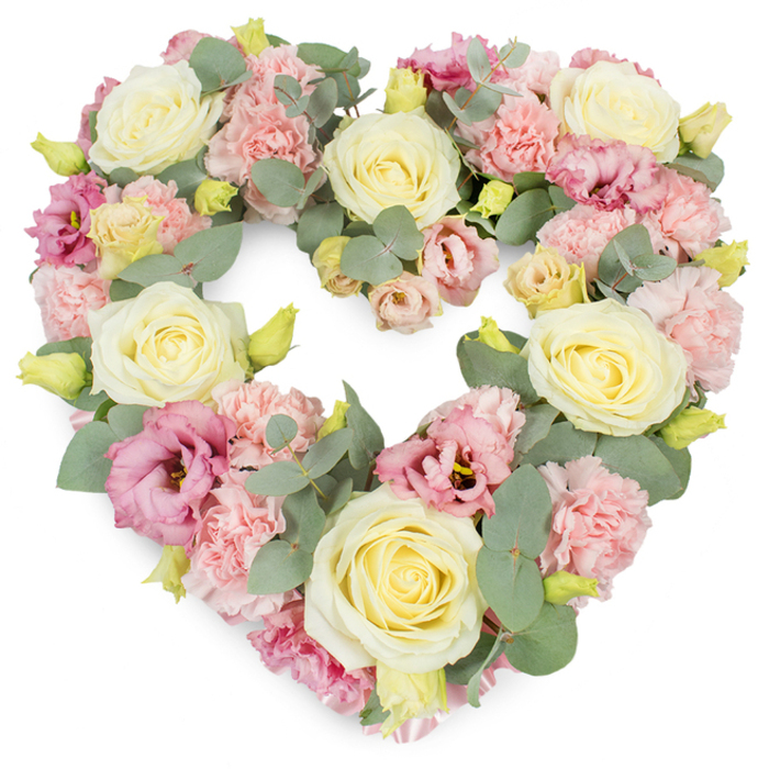 A luxurious heart-shaped floral tribute is displayed against a pristine white background, the outline of the heart clearly defined by dense, carefully placed flowers. At first glance, the eye is drawn to the generous cream and pale yellow roses that punctuate the design; their velvety petals swirl tightly from the centre, opening just enough to convey fullness and quiet grace. Surrounding these roses are clusters of light, ruffled pink carnations whose intricate, frilled petals add softness and a romantic, almost cloud-like texture. Scattered among them are deeper tones of mauve and magenta-pink lisianthus, their open, cup-shaped blooms and occasionally visible darker centres bringing depth and a subtle contrast that enriches the pastel palette without disturbing its serenity. Threads of silvery-green eucalyptus weave through the flowers, their rounded leaves adding cool, calming notes and a hint of woodland freshness. Small yellow-green buds appear here and there, lending a sense of new growth and vitality amid the more mature blossoms. The heart is fully packed, with blooms placed so closely that the arrangement appears plush and abundant, like a floral embrace. The overall composition radiates love, remembrance, and respect, making it particularly suitable for funerals, memorial services, and moments of farewell around Harrow on the Hill. You can imagine this heart resting near a casket or urn, or displayed at a service overlooking the historic hill, offering comfort to family and friends. The white background isolates the colours and shapes, ensuring the heart-shaped wreath itself is the sole focus-a delicate yet powerful symbol of sympathy and enduring affection.